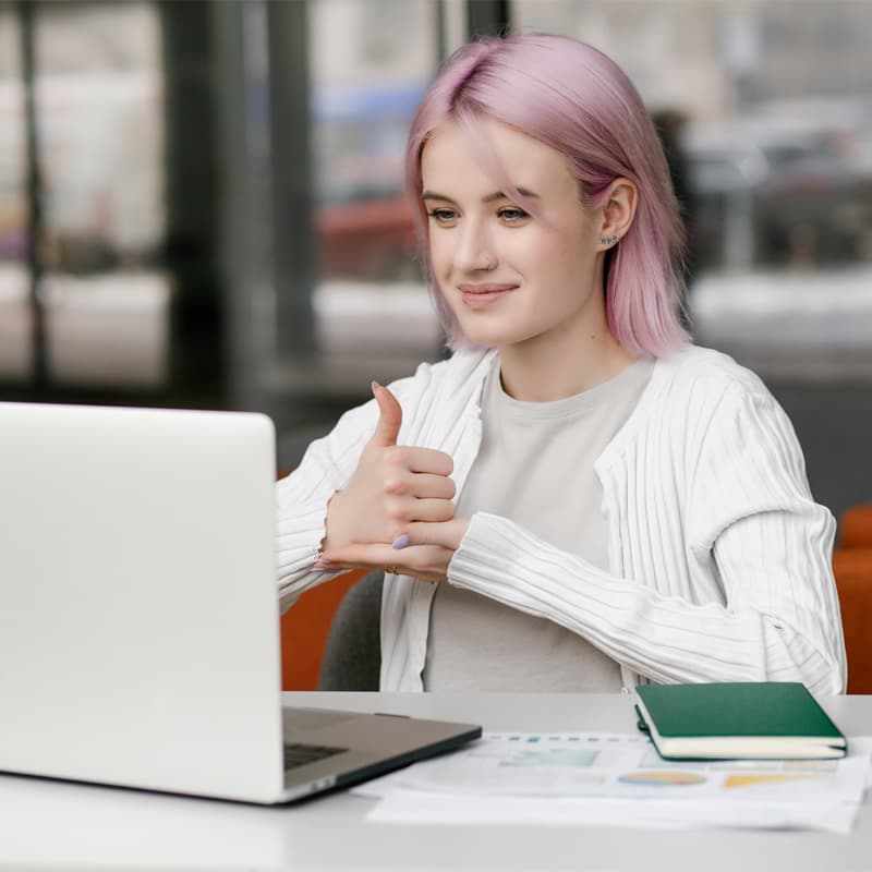 Young deaf businesswoman have digital virtual online conference with employees on computer, talking on video call, using sign language, showing gestures at screen.