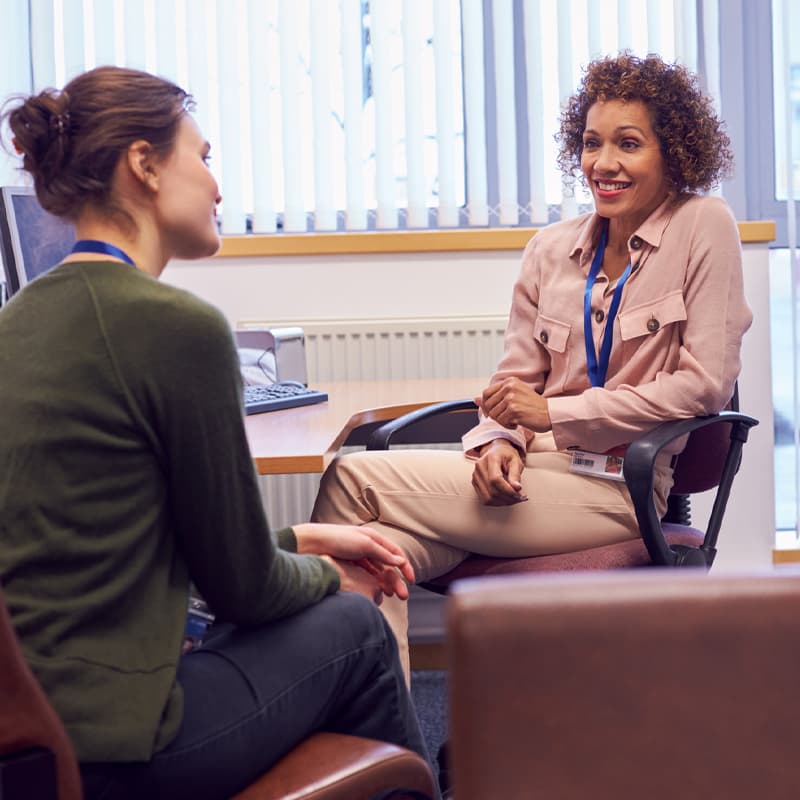 Female College Student Meeting With Campus Counsellor Discussing Mental Health Issues.