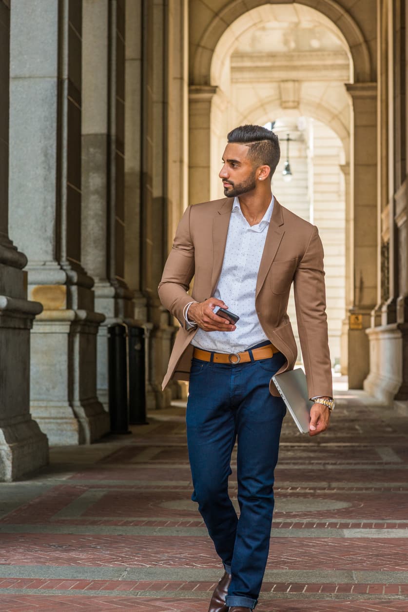 Man walking in blue trousers and brown jacket
